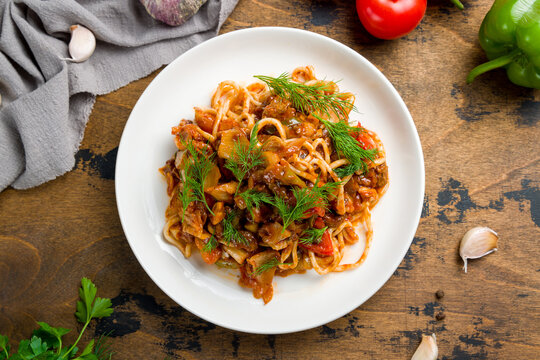 fried lagman with beef on plate on wooden table top view
