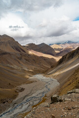 Vertical shot of a colorful mountain valley with a river on a cloudy day , Chile