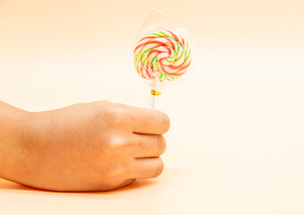 lollipop candy in a hand isolated on colorful background,