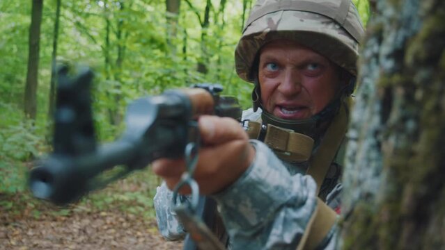 Close up face man soldiers holding machine gun forward to attack enemy in forest. Machine gun barrel look at camera.
