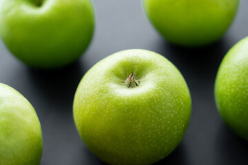 close up view of green ripe apples on black.