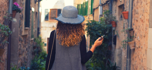 Young woman walking the cobblestone streets of an old tourist sea town