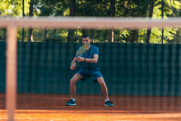 Strong male tennis player observed through the tennis net