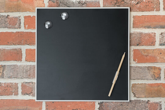 Ardoise avec tour argenté sur mur en papier peint imitation briques rouges. Vide, pour texte libre.