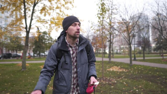 Inattentive adult Caucasian lost his husky dog in park and trying call pet, paying attention to poop holding in hand. Absent-minded person search pets, attracts attention with bone-shaped pet treat.