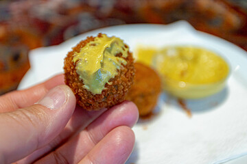Selective focus of a man hand with bite bitterballen, Dutch meat-based snack served with mustard, Typically containing a mixture of beef or veal, Bitterball are one of Holland's favorite snacks.