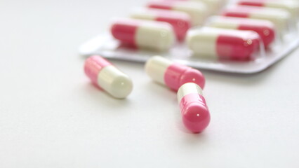 Pink-green pill capsules were placed on a white table.