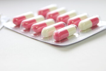 Pink-green pill capsules were placed on a white table.