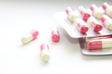 Pink-green pill capsules were placed on a white table.