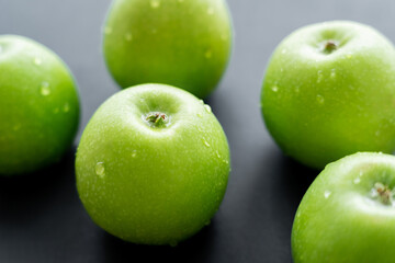 close up view of water drops on green and ripe apples on black.