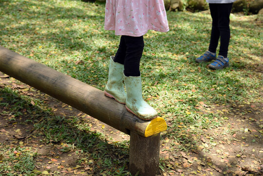 Girl walking along a wooden log in the park. Stability balance. Motor skills concept. Child on balance beam. Waldorf pedagogy