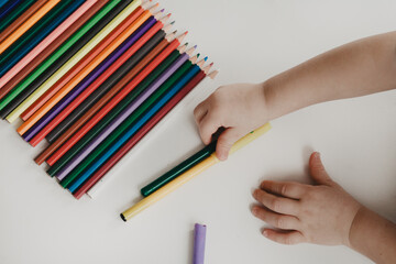 Children's hands reach for pencils on a white background