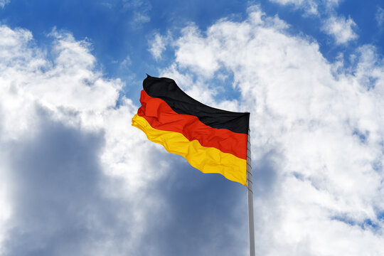 Flag of Germany in front of blue sky and clouds