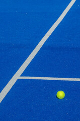 blue paddle tennis court, a solitary ball close to the baseline
