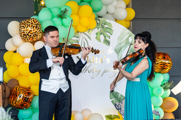Violinists play violins on a background of colorful balloons