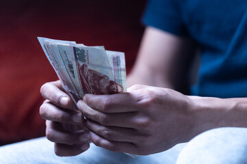man holding and counting Egyptian paper currency 