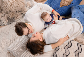 Young family dad moms and son lie on the carpet on the background of the New Year tree. High quality photo