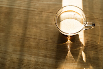Black coffee in the morning with sunlight, a cup of americano on the wood table in the cafe, clear glass of hot​ coffee ​ on​ the wooden​ table background.