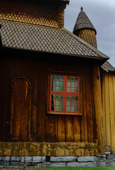 Fototapeta premium Details of the Lom stave church in Lom, Norway: tiny door, window, wooden tiles of the roof, small tower and stone basement