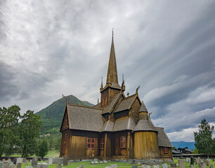 Fototapeta na wymiar Dramatic clouds in the sky above the Lom medieval wooden viking age stave church in Lom, Norway