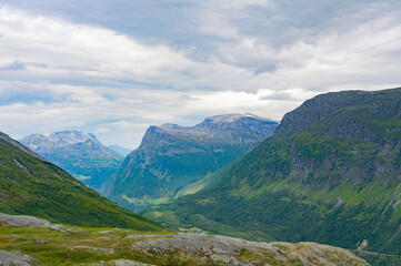 Norwegian summer landscape. Green and grey rocky mountains, mossy stones, cloudy sky