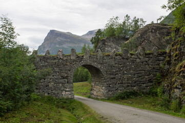old stone bridge in Norway, near Geiranger. Misty mountains and cloudy sky on the background