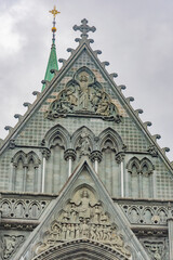 Fototapeta premium Nidarosdomen gothic cathedral in Trondheim, Norway. lilac sky with grey clouds, grey medieval stone walls and bell towers, figures of the saints in arches