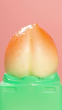 beauty peach shape popsicle melting on pink timelapse at vertical composition