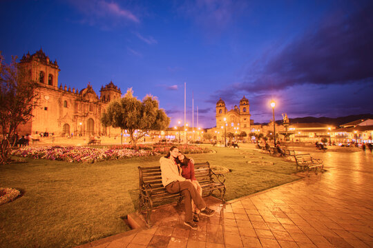 Pareja de turistas sentada disfrutando de la plaza principal de Cuzco.