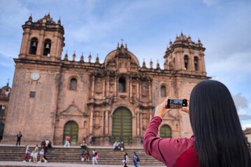 Turista de espaldas tomando una foto de la catedral de Cuzco