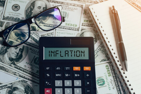 word inflation on the calculator on banknotes with glasses and notebooks with pens on them The concept of FED considers interest rate hike, world economics, inflation control, US dollar inflation