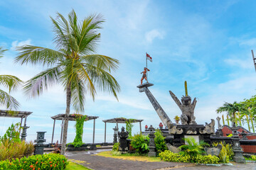Buleleng harbour with it's icon Yudha Mandala Monument by the sea, blue sky background