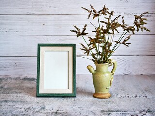 Grass in vase on table and old vintage background Empty photo frame ,Cyperus haspan flowerhead dry grass still life ,copy space for letter ,wooden old wall black and white ,old style ,flowers in vase