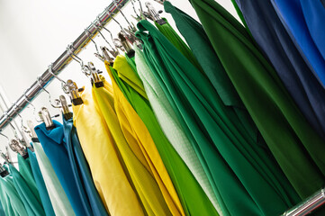 Samples of green yellow and blue fabrics hang on rack bar