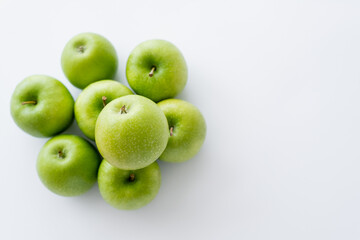 top view of green and fresh pile of apples on white.