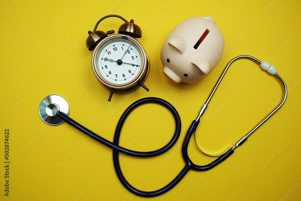Poster alarm clock with piggy saving and stethoscope top view on yellow background