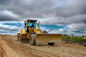 a grader on the construction site levels the rubble