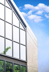 Geometric pattern of steel and glass wall on office building in loft style against blue sky background in vertical frame