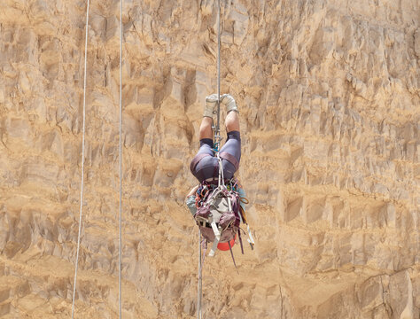 An experienced athlete athlete descends upside down with the equipment for snapping in the mountains of the Judean Desert near the Tamarim stream near Jerusalem in Israel