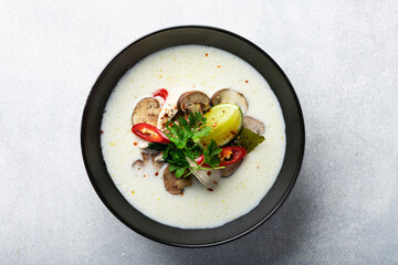 Tom Kha Gai, Thai Galangal chicken coconut soup in a black bowl on a concrete background, top view