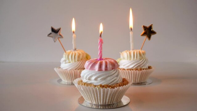 birthday cupcakes with candles and birthday decorations on a light background