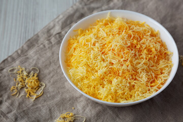 Shredded Mexican Cheese Mix in a White Bowl, side view. Close-up.