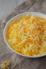 Shredded Mexican Cheese Mix in a White Bowl, low angle view.
