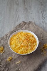 Shredded Mexican Cheese Mix in a White Bowl, side view. Space for text.