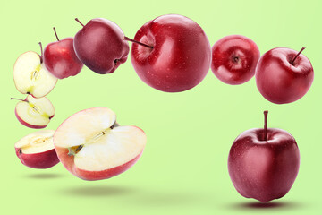 Ripe red flying apples and halves on green background