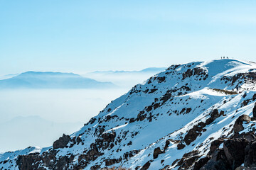 Horizontal shot of the top of snow-capped Provincia mountain with fog in the background, Chile.