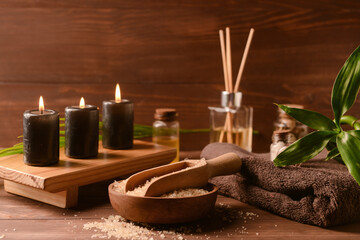 Bowl of sea salt, clean towel and burning candles on wooden background