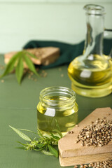 Jar of hemp oil and seeds on color wooden background