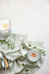 Holders with burning candles and eucalyptus branches on light background