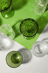 Stylish empty glasses on color background